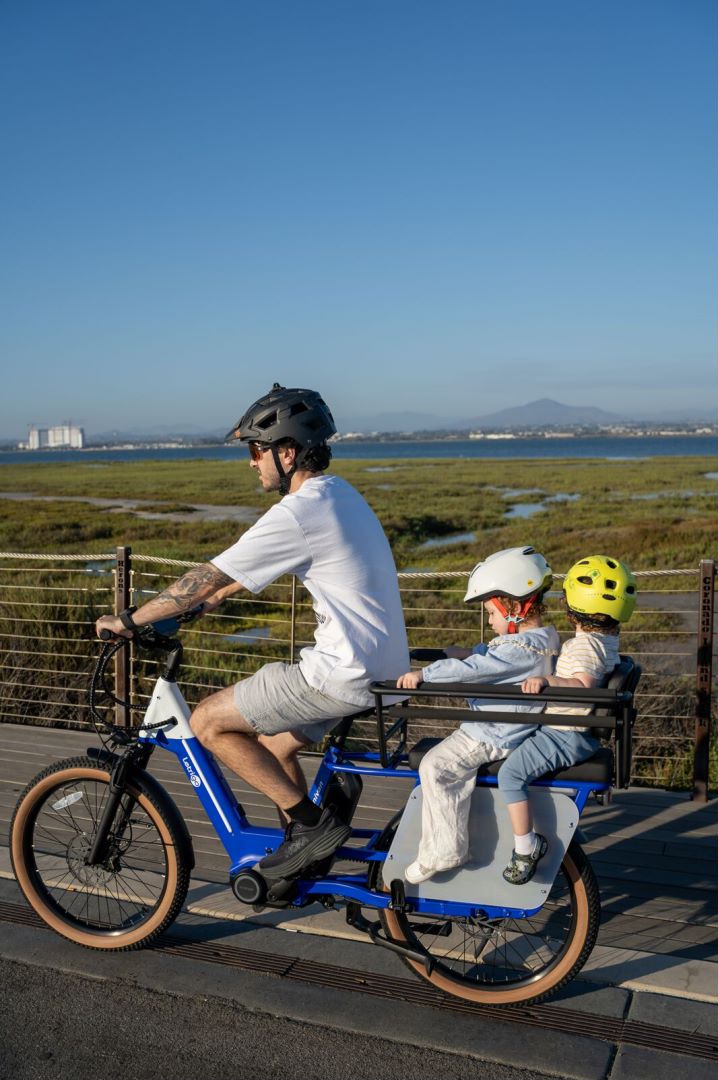 Father riding a Minivan Cargo Bike with two children